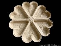Top view of the cream-colored ceramic shortbread mold showing detailed embossed heart-shaped segments and floral center