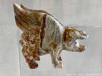 Side view of the carved stone pig figurine with wings, showing detailed texture and coloration.