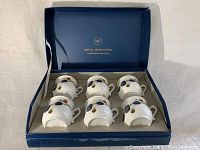 Six Royal Worcester chocolate cups arranged inside original blue box with fitted slots