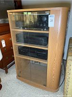 Full view of oak-finish cabinet with double glass doors housing audio components