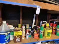 Shelf with assorted chemical containers including large jugs, spray cans and smaller bottles