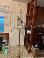 Full view of gold-tone tension pole floor lamp with three shades and tension top cap