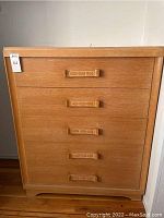 Front view of five-drawer dresser showing light brown solid wood finish and carved wood handles
