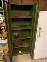 Interior view of the same cabinet showing four shelves with visible stains and spills on the shelf surfaces and interior walls.