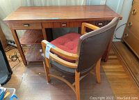 Photo showing solid wood office desk with drawers and shelves, and wooden arm chair with padded seat and backrest