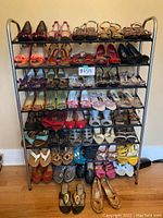 Full view of the metal shoe rack loaded with 43 pairs of women's shoes, various styles and colors.