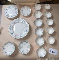 Full set of 50 pieces laid out including plates, cups, and saucers showing the matching floral Pastoral pattern by Royal Doulton.