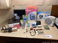Wide view of all assorted electronic items on display including fan, heater, TV, speakers, projector, power strip and accessories.