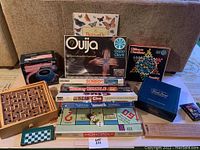 Full lot view showing all boxed and loose games including Monopoly board laid flat and other stacked boxed games