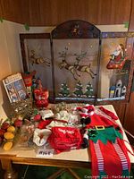 Photo of entire lot on table including fireplace screen, Santa sack, elf aprons, candles, wine bottle covers, clown mask, and witch noses.