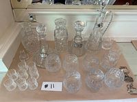 Overall view of assorted crystal decanters and glasses on a table with a reflection in the background mirror