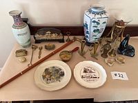 Overview photo of the lot showing all decorative items including vases, plates, brass pieces, figurines, and cane.
