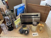 Full lot displayed including FoodSaver vacuum sealer, Miracle Mixer blender with cups, soup pot, coffee grinder, mini chopper, bakeware liner and cutting board.