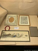 Four frames and red horseshoe arranged on flat surface for display; frames vary in size and style with one ornate and one natural wood, plus figurative art and empty frame
