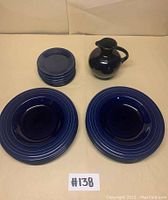 Full view of the lot including 1 decanter jug, 8 side plates stacked, 7 dinner plates shown in front, all in bright royal blue ceramic glaze.