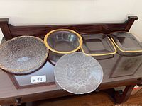 Photo showing all five glass platters displayed on a wooden surface, including varied shapes and gold accents.