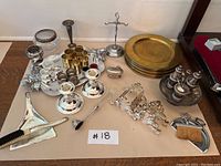 Full overview of all sterling silver, silver plated, brass dining ware items on a table including plates, candle holders, napkin rings, and other accessories.