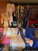 Overview photo showing multiple vintage robes in various colors and patterns displayed hanging and draped over furniture.
