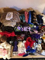Top view of winter scarves, mink earmuffs, hair bows, and gloves spread out on a surface.