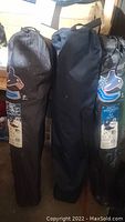 Three camping fold-up chairs in black carry bags, two with Vancouver Canucks logos visible, one without visible branding.