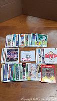 Photo showing multiple stacks of baseball cards arranged on floor, including both modern and vintage styles, with a sign indicating 402 baseball cards