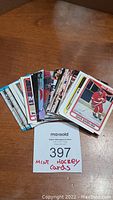 Photo showing a spread of approximately 50 hockey cards fanned out on a wooden surface. One card visible shows player Dave Barr in Detroit Red Wings uniform.