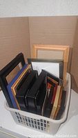 Basket filled with small to medium picture frames of different colors and materials