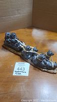 Full view photo of soapstone dogsled sculpture showing seven huskies and musher sitting on the sled. Sculpture rests on a polished flat base resembling a classic sled.
