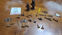 All items arranged on a wooden surface showing the full lot: tie clips, cuff links, and two brass statues.