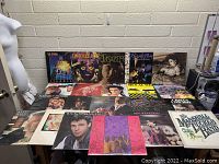 Overview of assorted 1980's vinyl records laid out on table showing album covers of various artists.