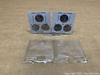 Lot showing two display cards each containing three 1943 steel pennies with mint marks D, P, and S, plus two empty plastic holders.