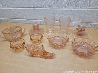 Front view of all pink glass items arranged on a table showing variety of shapes and patterns.