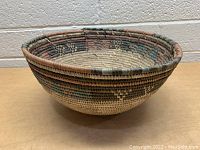 View of woven basket showing geometric diamond pattern and earth tone colors