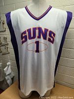 Front view of white Phoenix Suns basketball jersey with purple sides and number 1.