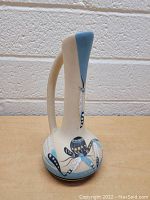 Side view of the vase showing handle and painted dragonfly motifs on base and neck