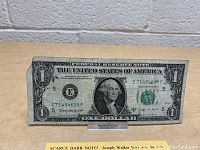 Front image of the worn Series 1963 B $1 Federal Reserve Note showing George Washington, serial numbers, and treasury seal.
