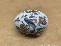 Oval egg-shaped box with detailed colorful crane and floral motifs on the top and sides.