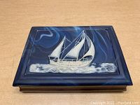 Top view of vintage wooden jewelry box with detailed sailboat inlaid stone artwork on lid.