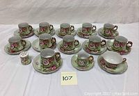Full set of 12 tea cups and 12 saucers plus ceramic shaker displayed on white cloth background.