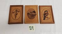 Front view of three framed marquetry art panels showing floral and bird designs.