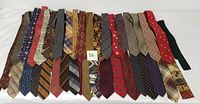 Photo showing 26 assorted men’s neck ties laid out side by side displaying various colors and patterns including stripes, paisleys, plaids, and solids.