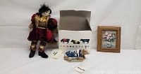 Puss in Boots doll, Cow Parade MooShoe figure with original box, framed floral still life painting arranged side by side.