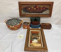 Grouping of oil paintings, Longaberger baskets, and vanity boxes on white cloth background