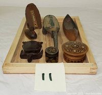 Top view of lot on a wooden tray showing seven items including wooden canoe, two turtles, duck, thermometer, and two trinket boxes.