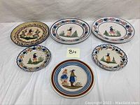 Six vintage Quimper hand-painted plates displayed on white backdrop, showing various folk art designs with traditional Breton figures and floral borders.