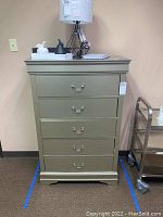 Front view showing five drawers with silver drop pull handles and metallic finish.