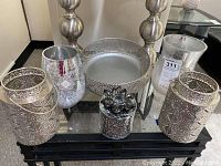 Overview of all items in the lot displayed together on a table including the glass candle holders, metal lanterns, metal bowl, and mirrored cup with lid.