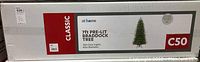 Box 1 showing label: 7ft Pre-Lit Braddock Tree, 300 clear lights, 42in diameter, brand 'at home', Classic series, new in box.