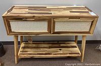 Full view of bamboo console table with two drawers and bottom shelf shown against wall.