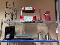 Wire metal soda can rack, hot dog maker, paper towel holder, Keurig coffee machine, George Foreman grill, and two metal canisters on shelves